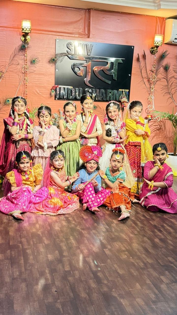 A larger group of students in colourful costumes posed together in front of the academy sign