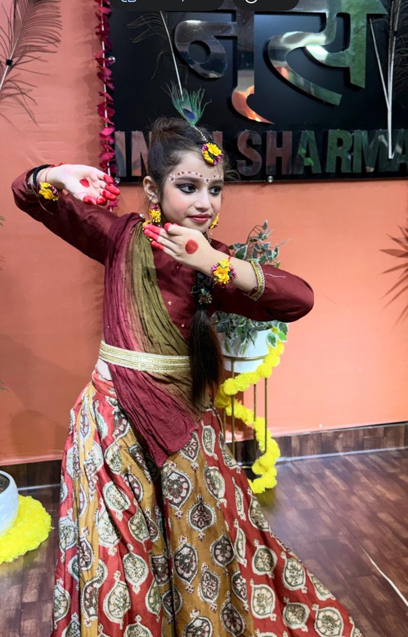 Student striking a Kathak pose in front of the academy sign